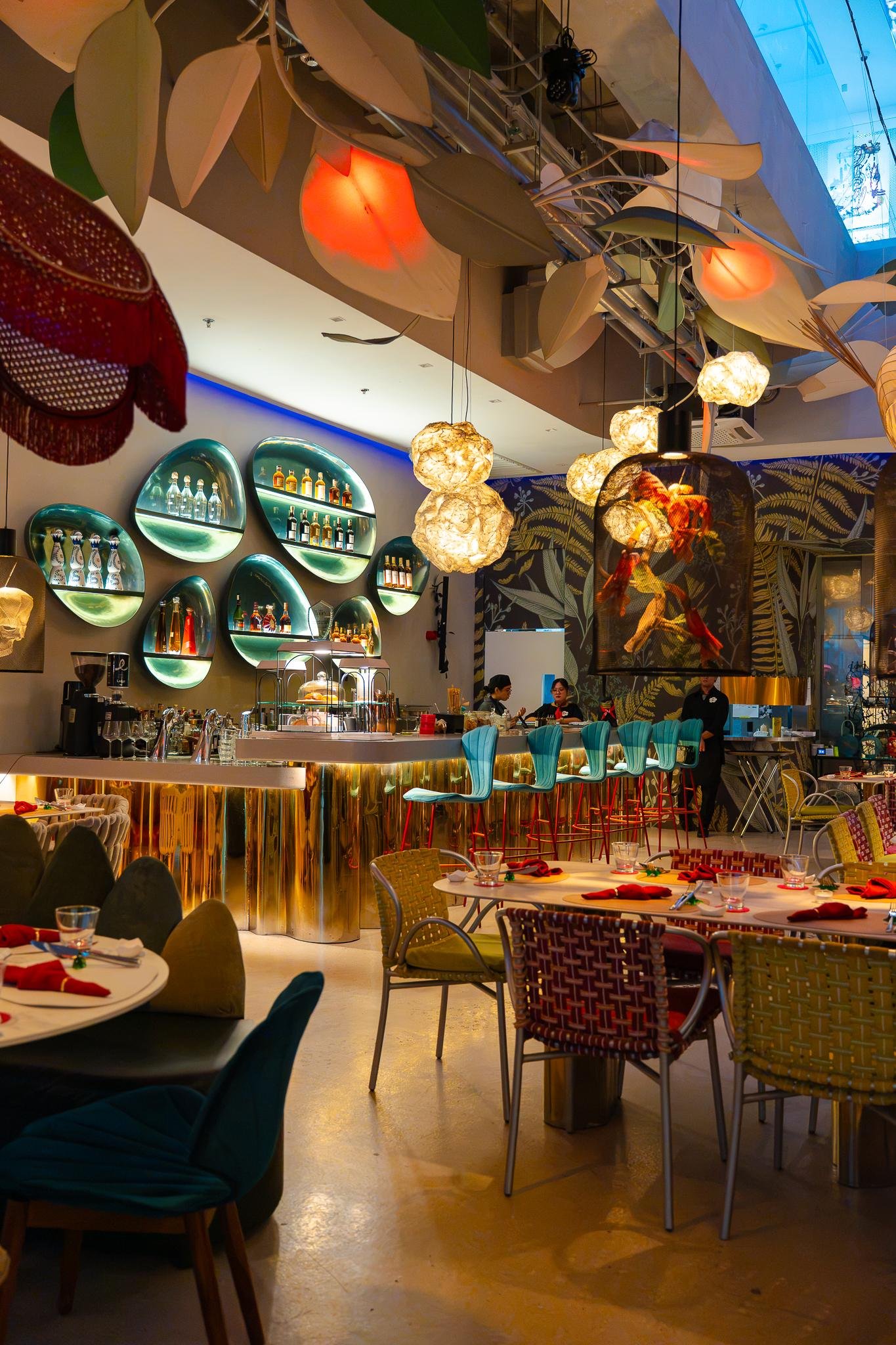 Fable Cafe and Lounge dining room with a gold-fronted bar and hanging leaf lights